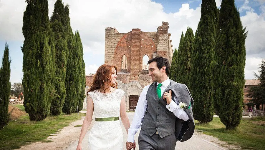 Val d'Orcia Bride and groom walking between cypresses at San Galgano, photo Studio Bonon