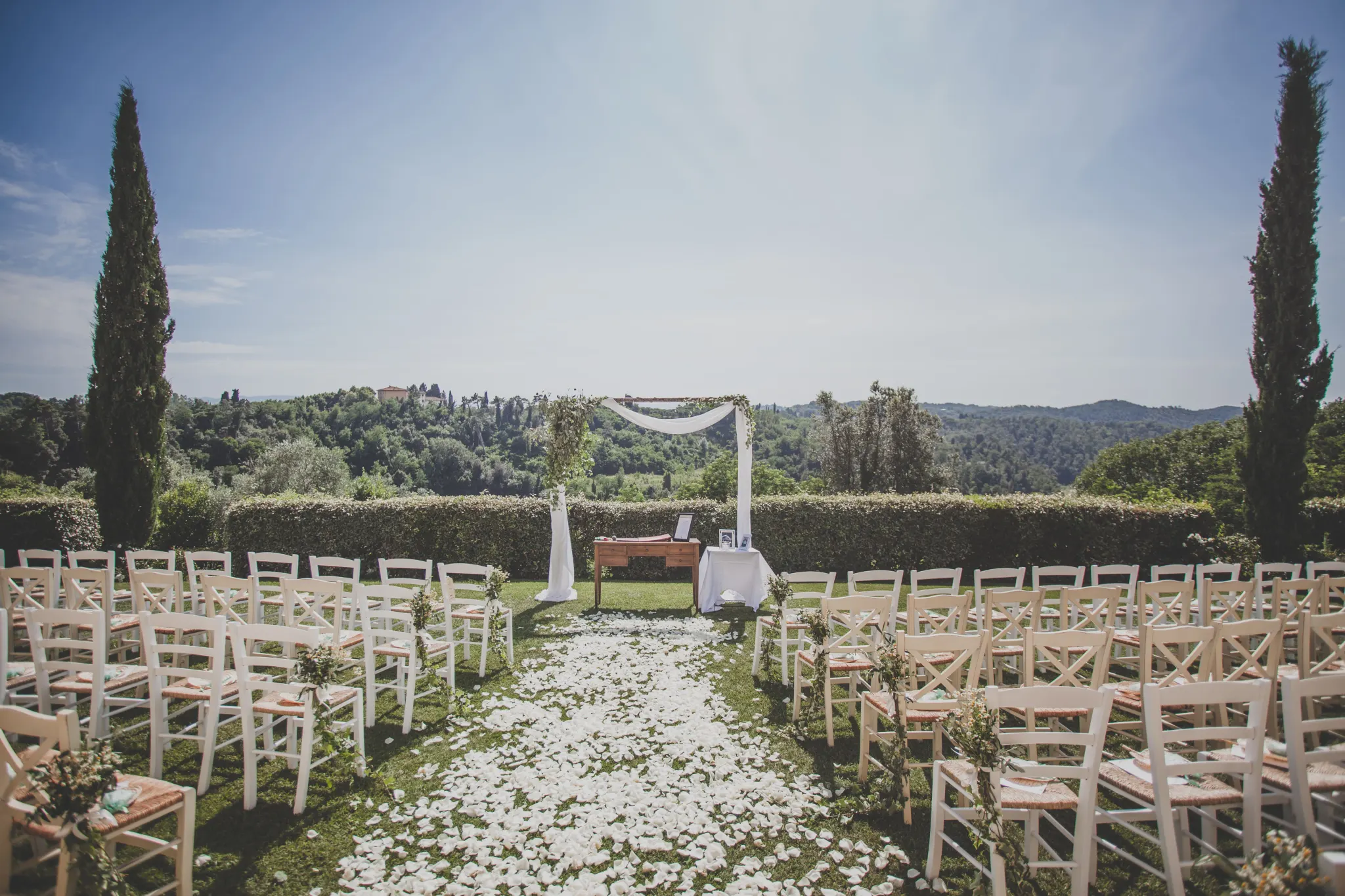 Ceremony aisle with white petals and a view over the Tuscan hills