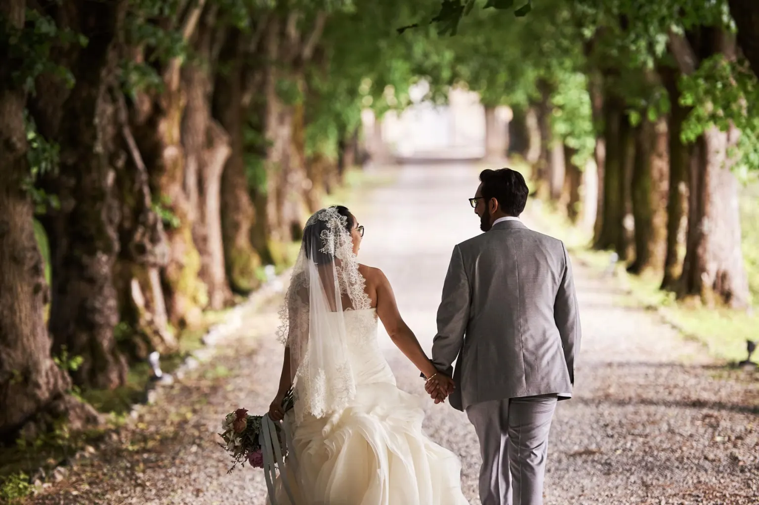 Two cities, Bride and groom walking along a tree-lined avenue in the countryside near Pisa
