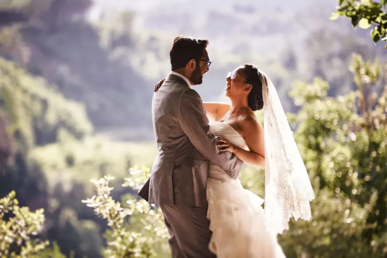 Bride and groom embracing with the Tuscan hills behind them