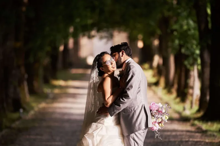 Bride and groom kissing on a tree-lined path near Pisa