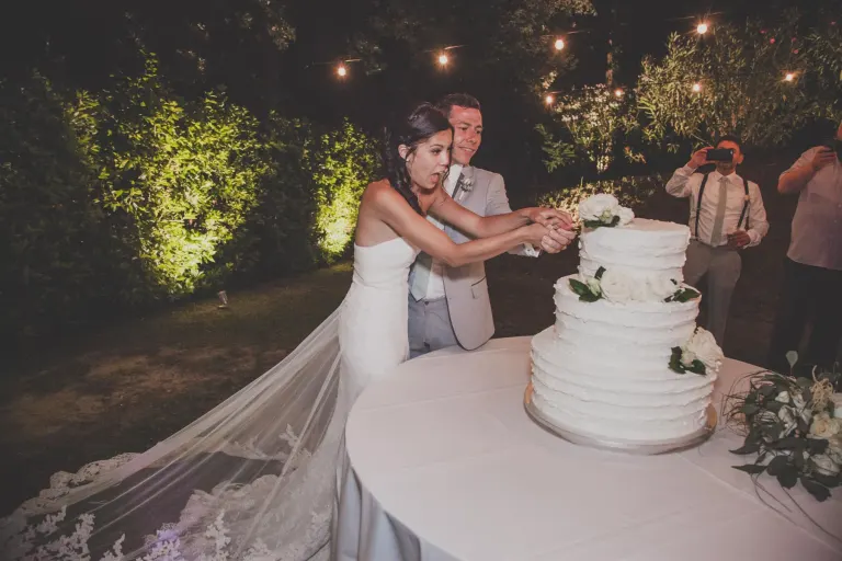 Bride and groom cutting the wedding cake at night