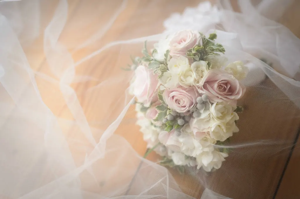 Elopements and micro weddings Bridal bouquet of pale pink and white roses under a tulle veil