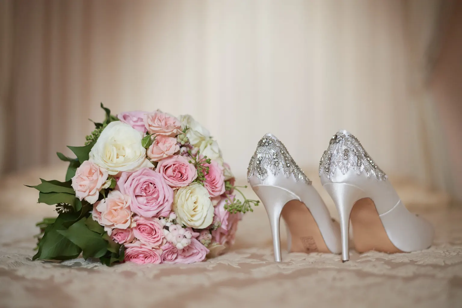 Silent, fragile, gentle: Bridal bouquet of pink and white roses next to the bride's shoes