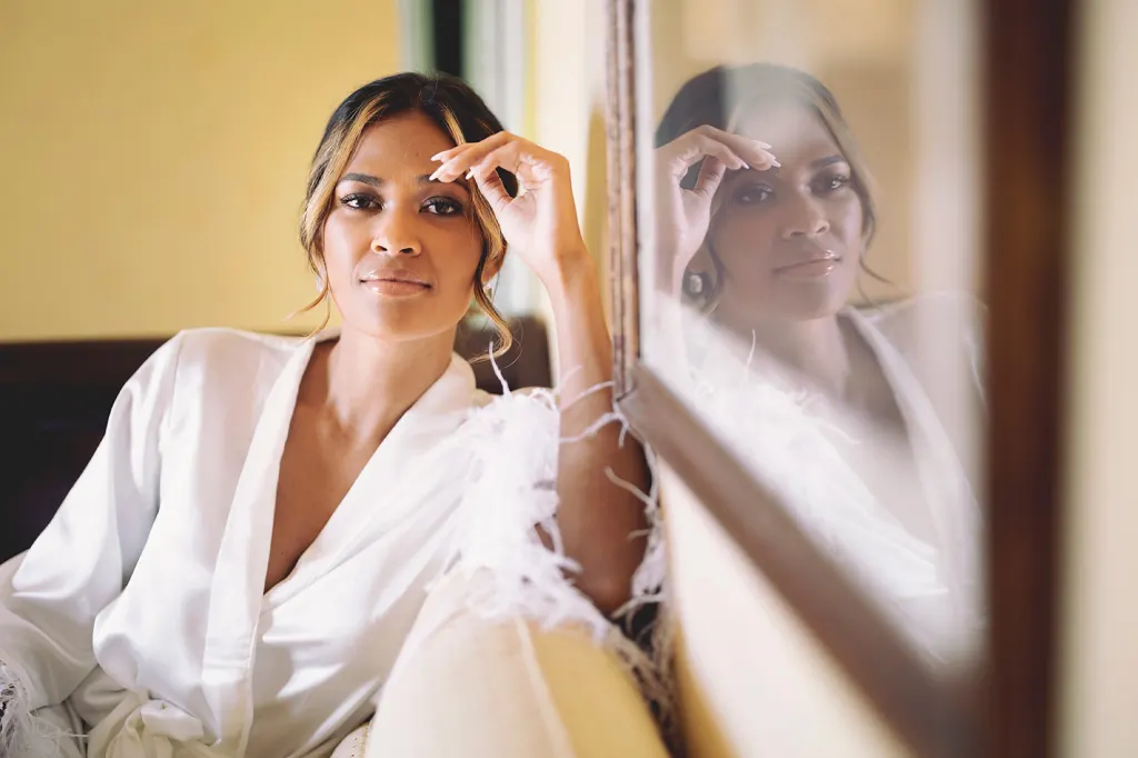 Hair and make-up Bride in a white robe getting ready by the mirror on her wedding morning in Tuscany, photo Daniele Vertelli