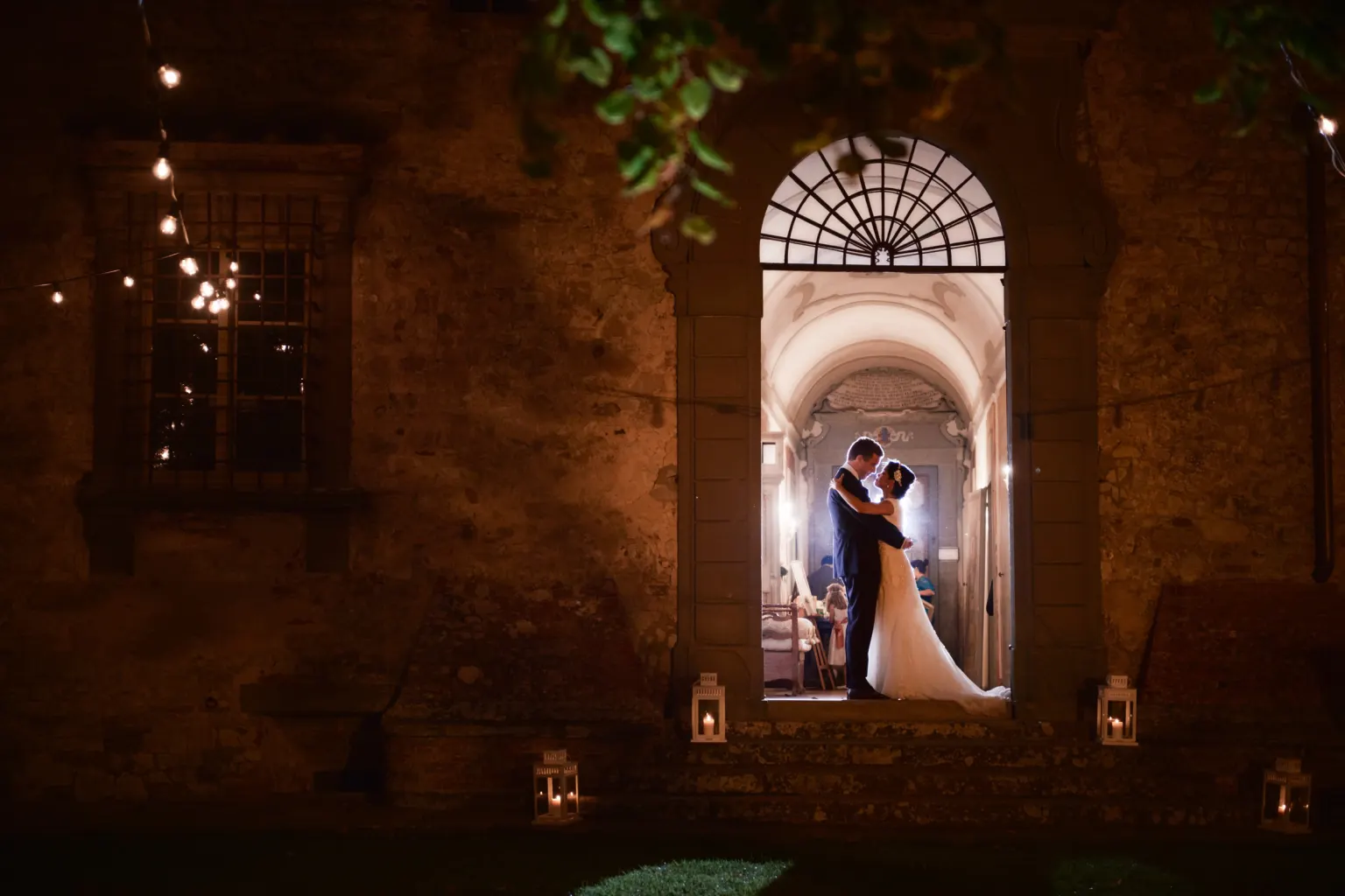 A wedding in a castle, Bride and groom kissing in a lit castle doorway at night