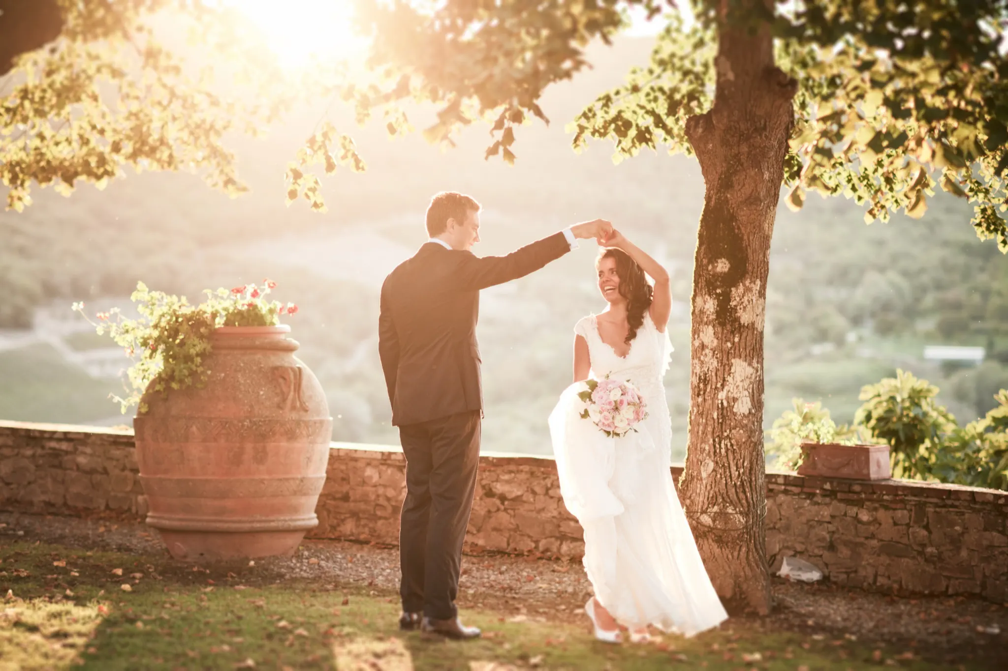 Bride and groom dancing under a tree on a terrace above the Tuscan hills