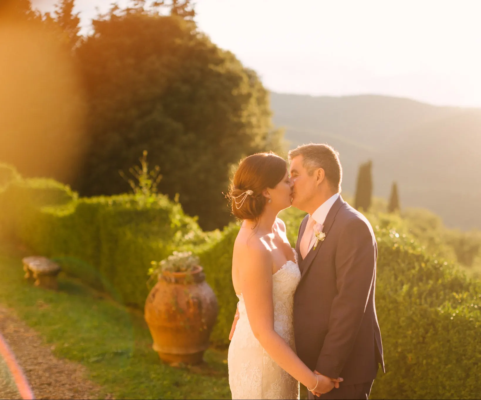 Bride and groom kissing at sunset in a garden overlooking the Tuscan hills