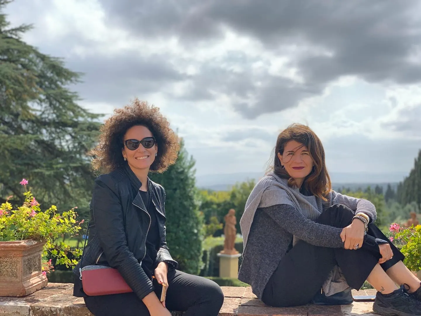 Francesca and her assistant Chiara sitting on a garden wall of a Tuscan villa