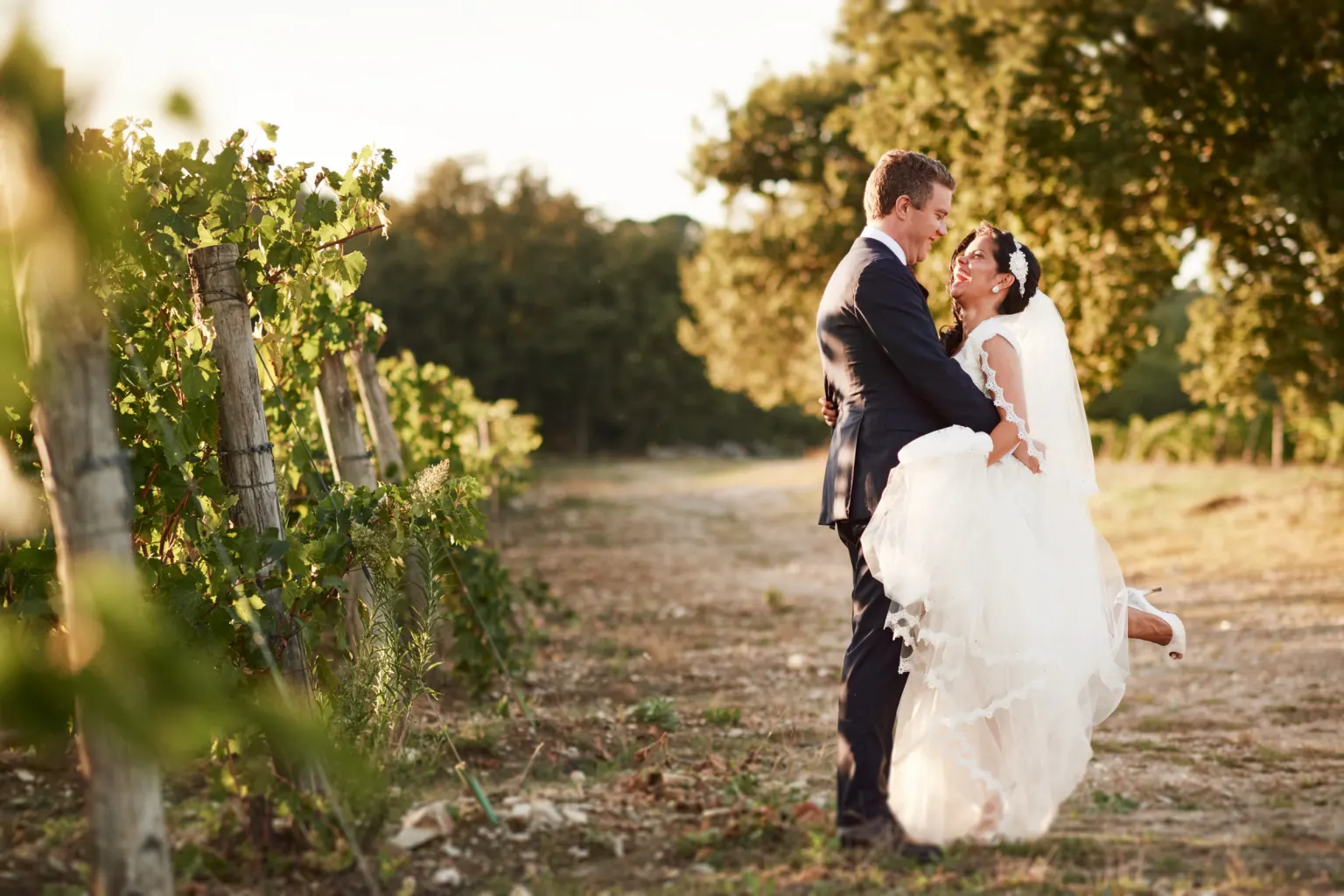 Nulla osta para casamento na Itália: Noivo carregando a noiva entre os vinhedos da Toscana