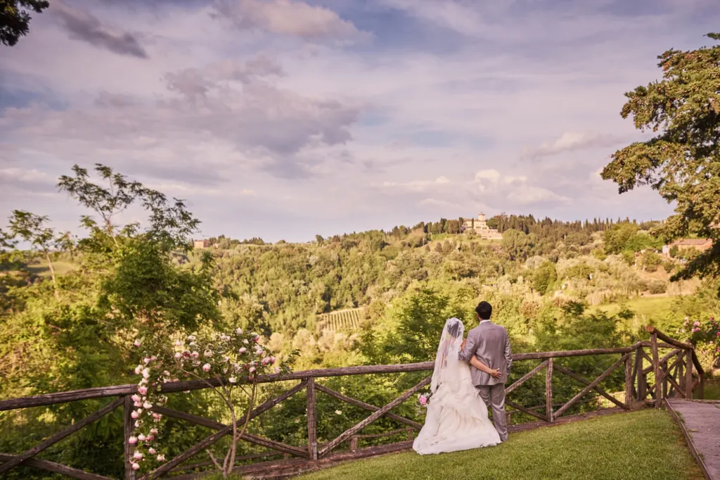 The wedding day Bride and groom looking out over the Tuscan hills next to a climbing rose