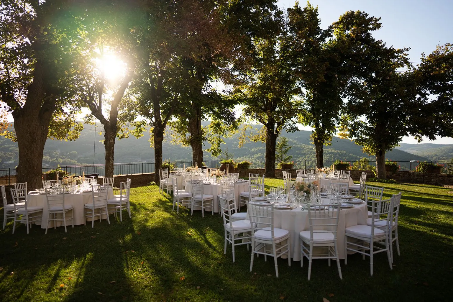 Beautiful, Round dinner tables under the trees at sunset with a view of the Chianti hills