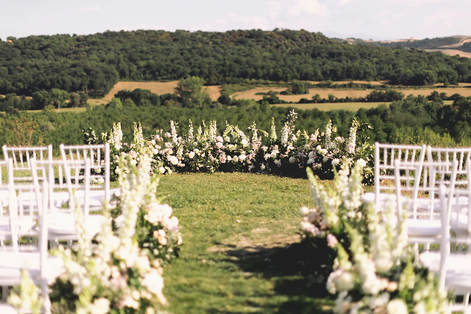 Efffetti® Wedding Planners In Tuscany - Italy Ceremony with a low arch of white flowers overlooking the Tuscan hills