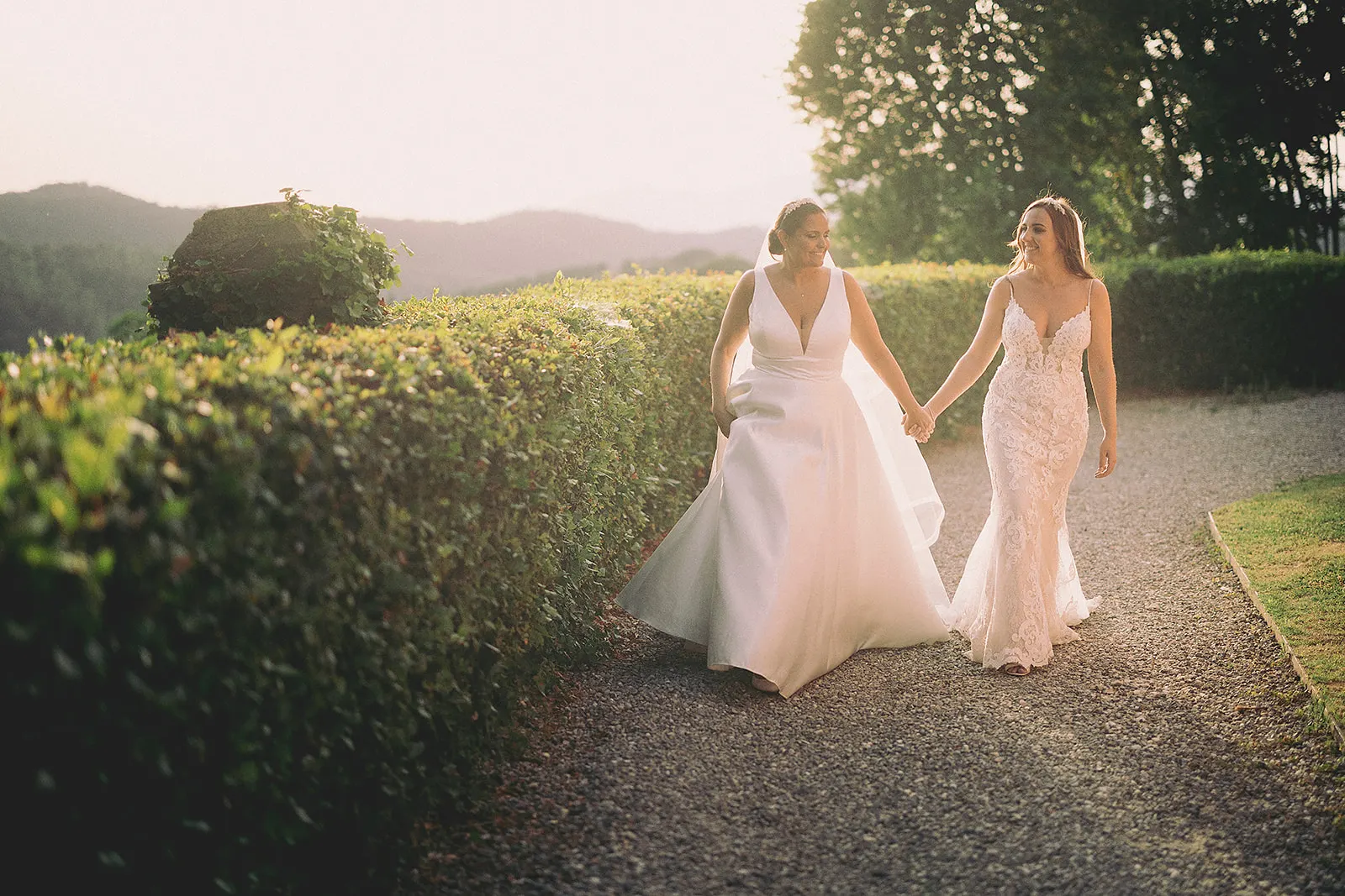 Efffetti® Wedding Planners In Tuscany - Italy Two brides walking hand in hand at sunset in Tuscany
