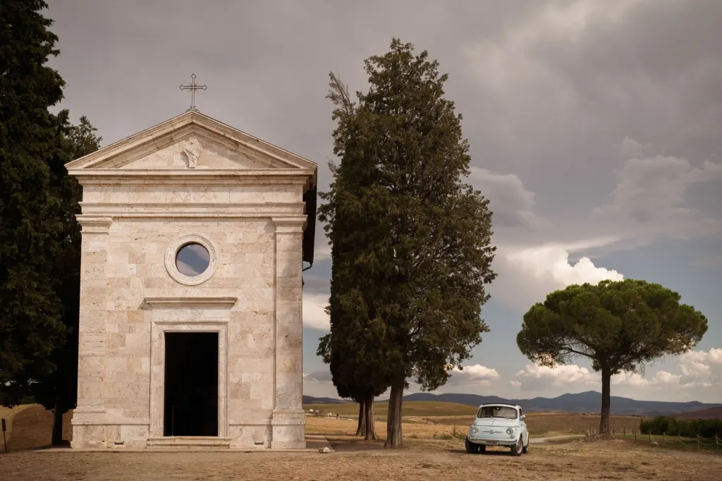 Wedding in Val d'Orcia The chapel of the Madonna di Vitaleta among cypresses, with a vintage Fiat 500