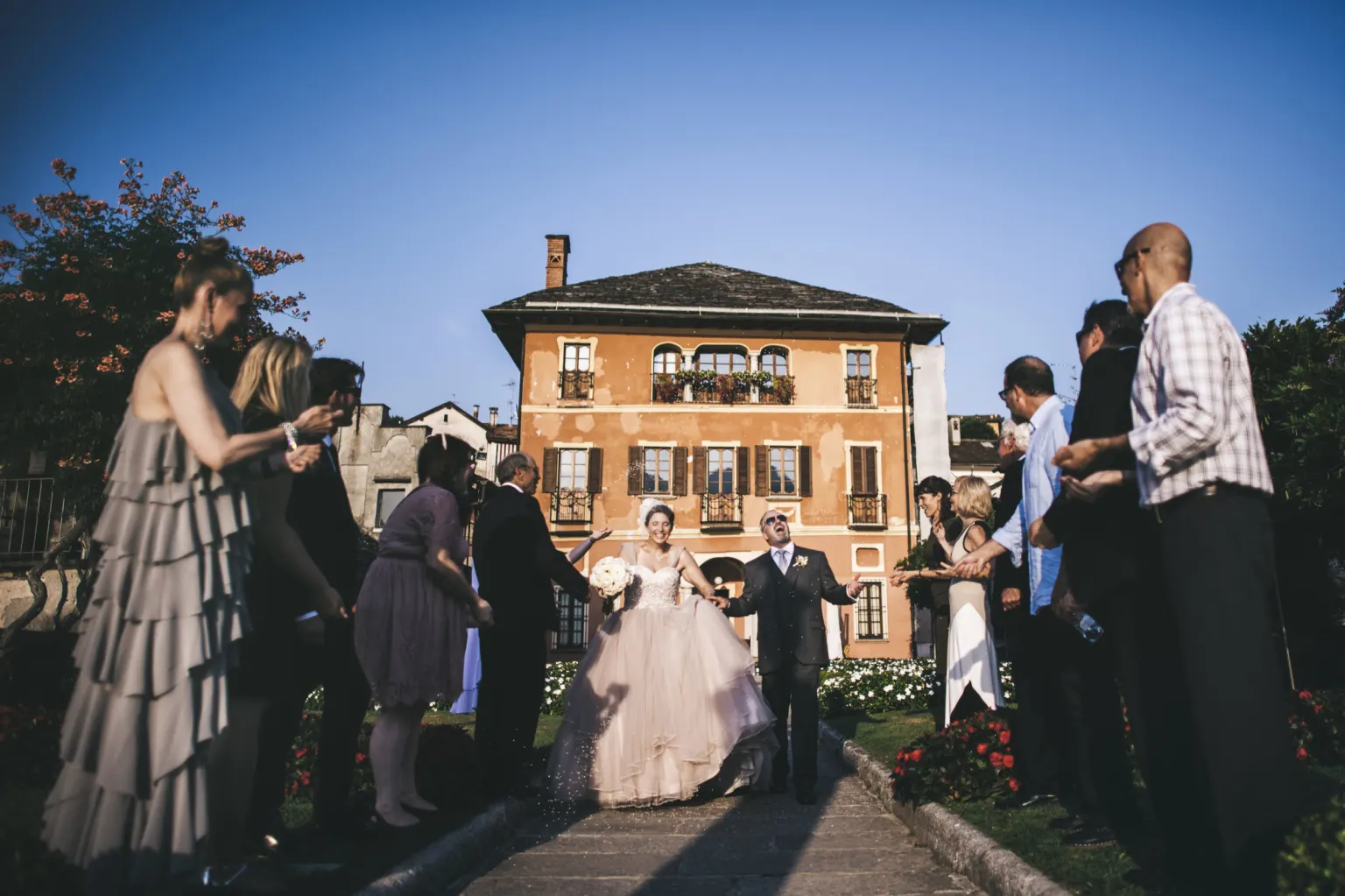 Bride and groom walking out of their ceremony between their guests in front of a villa