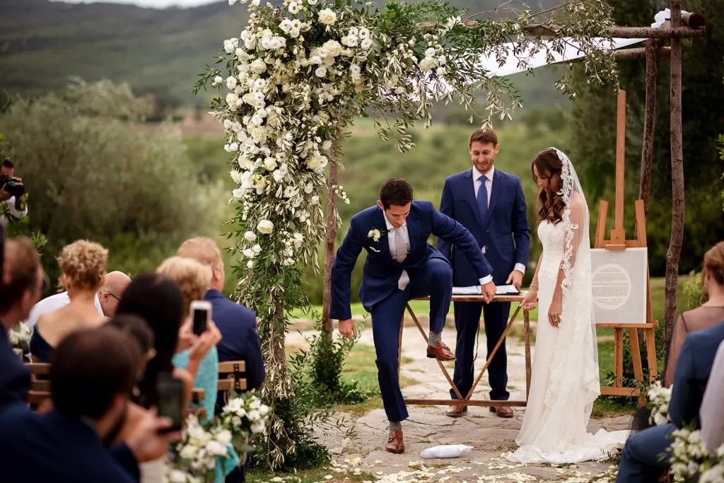 Wedding in Tuscany Outdoor wedding ceremony under an arch of white flowers in the Tuscan hills