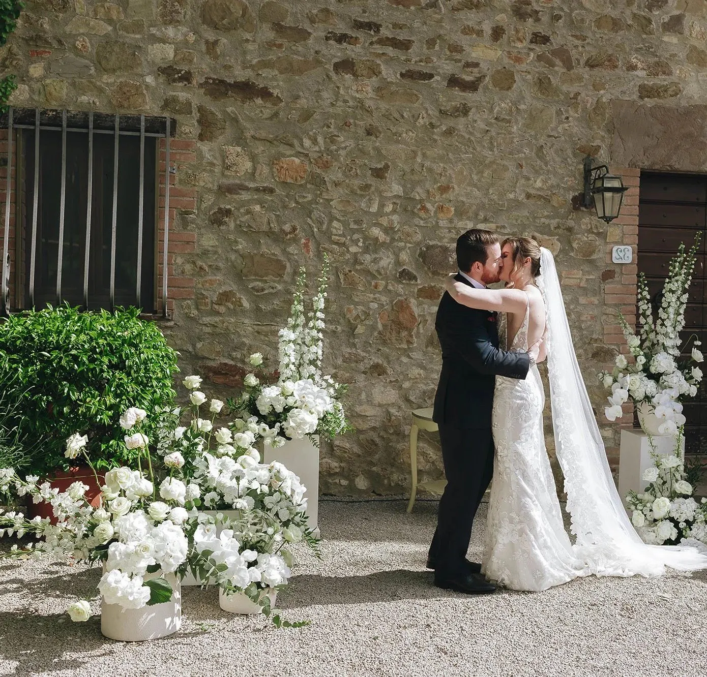 Efffetti® Wedding Planners In Tuscany - Italy Bride and groom kissing after their ceremony in the stone courtyard of a villa in Umbria